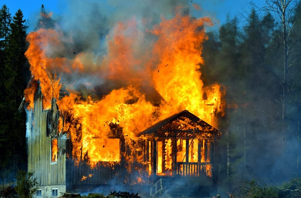 Flames engulf the house, bursting through the windows, door, and roof.