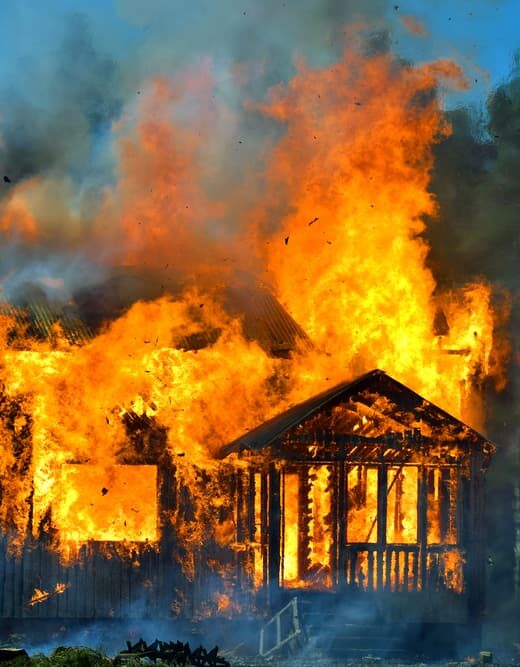 Flames engulf the house, bursting through the windows, door, and roof.