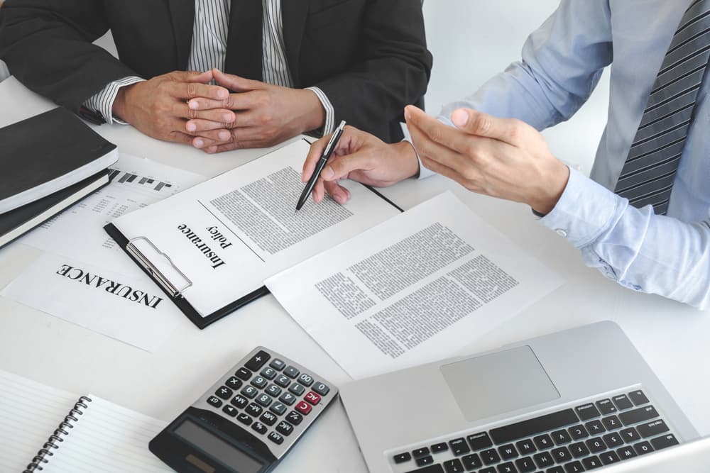 The image of an insurance agent explaining an insurance policy to a customer in an office setting.