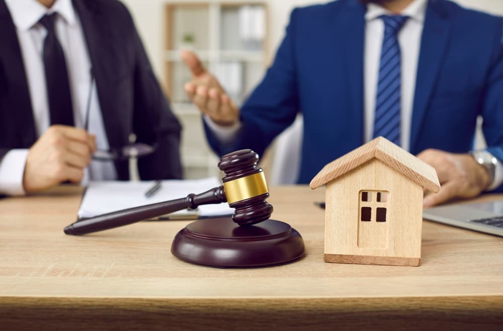 A lawyer and client negotiate a house mortgage agreement in an office setting, with a model home and legal documents.