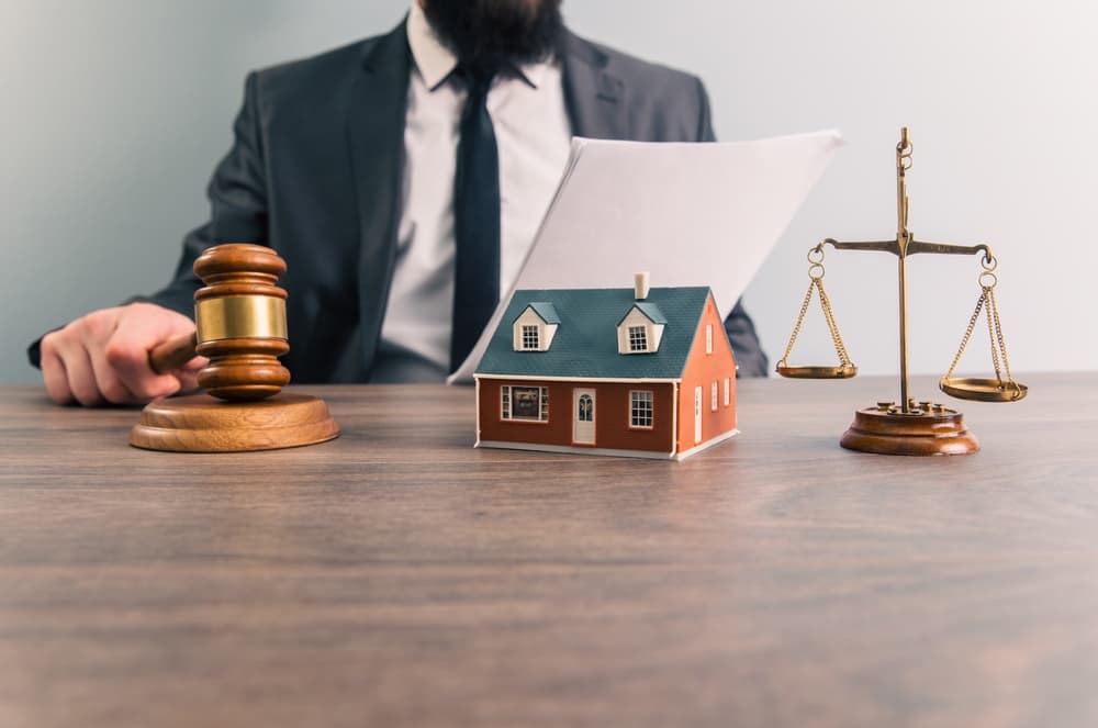 A close-up image of a judge's gavel resting on a wooden desk,  featuring a lawyer in a professional suit discussing housing and real estate law.