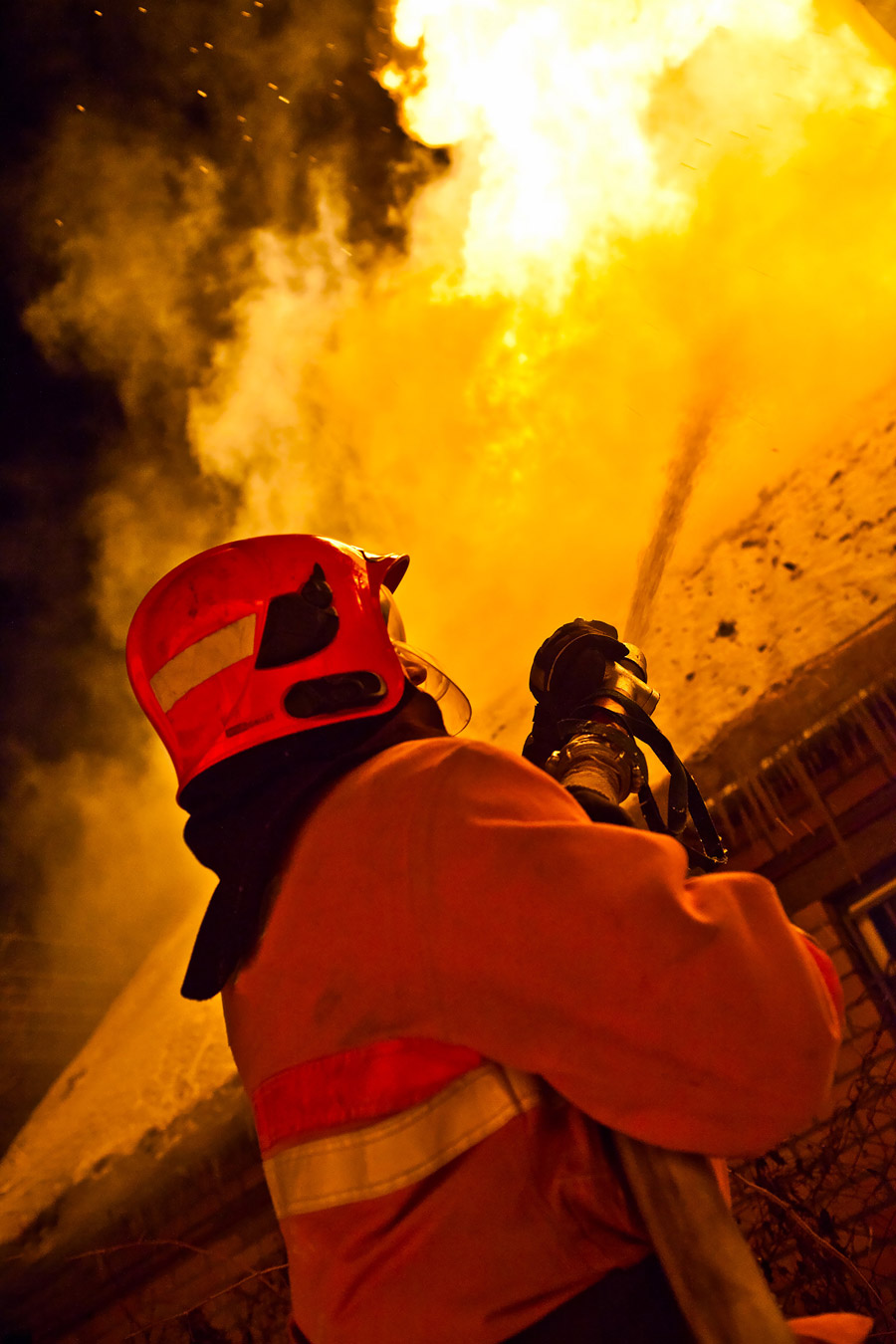 Fire damage evident as a firefighter battles the flames, needing a fire damage lawyer for claims