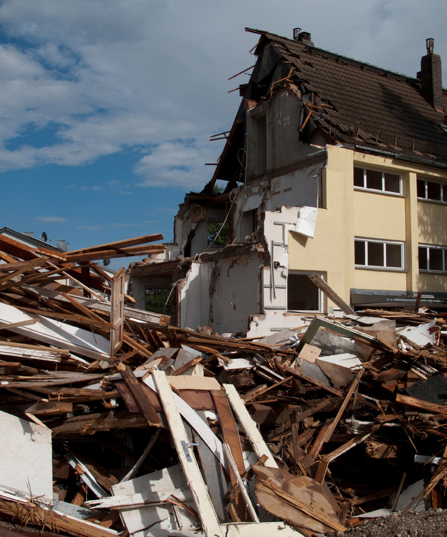 Tornado damage to a building, roof torn off, and debris scattered, needing a tornado damage lawyer for claims